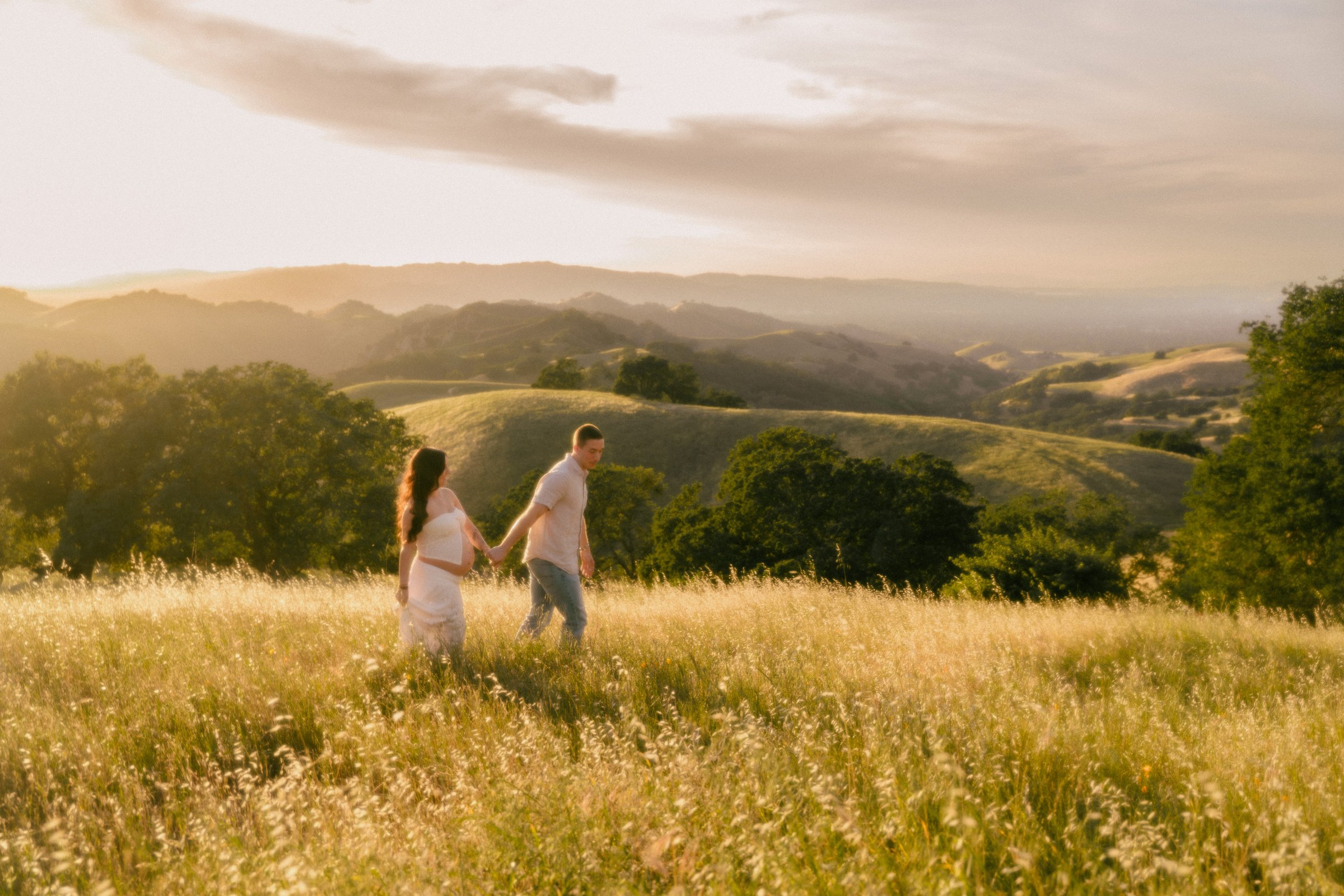 A couple walking through a golden field at sunset